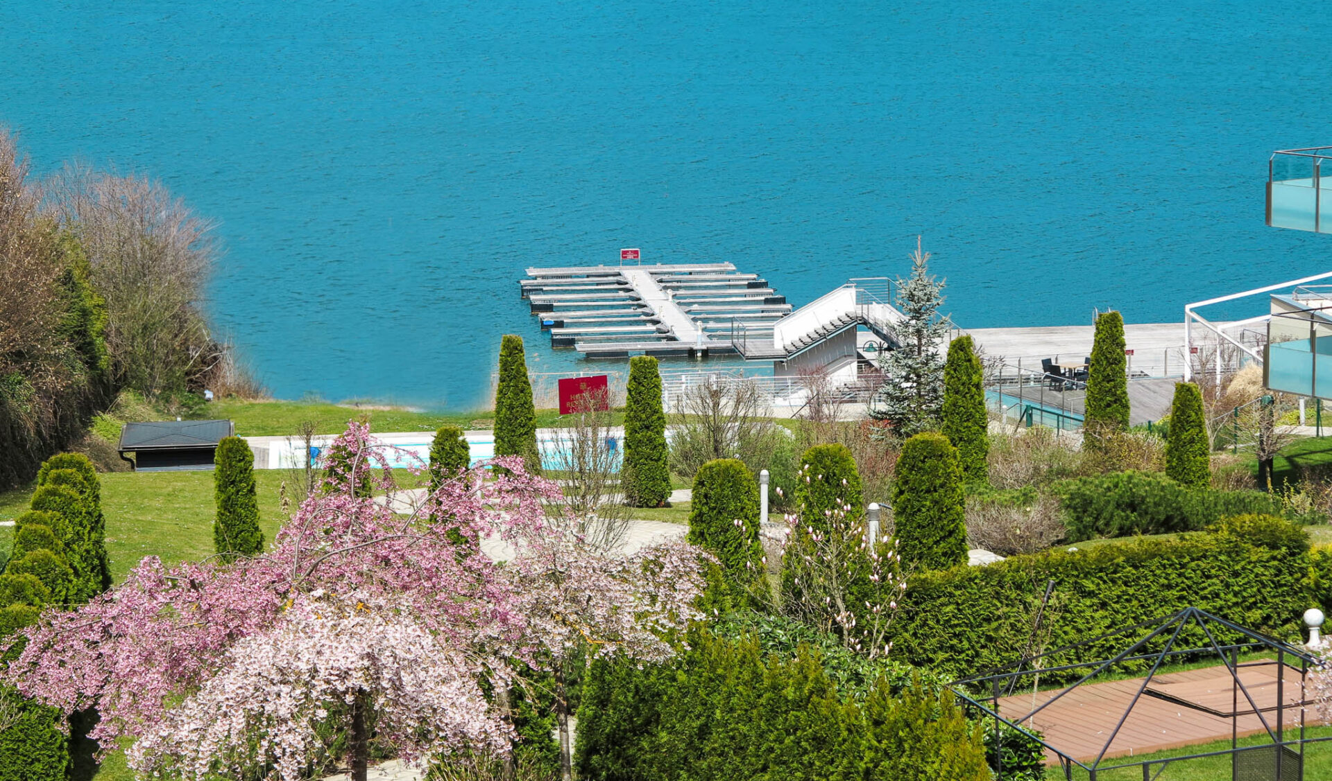 Ausblick auf einen See und blühendem Garten.