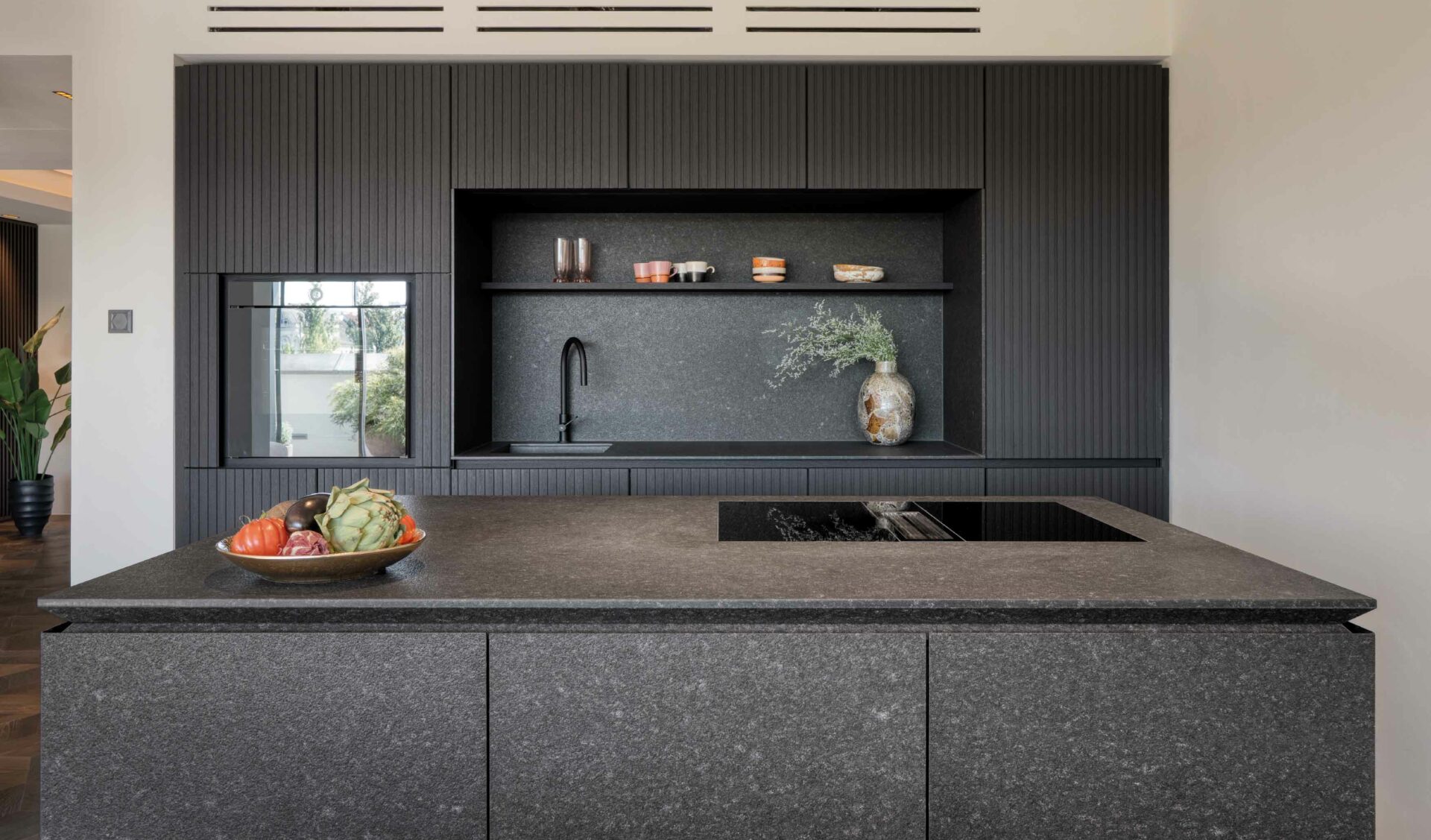 Moderne Designerküche mit schwarzer Kücheninsel, Steinarbeitsplatte und Lamellen-Hochschränken.