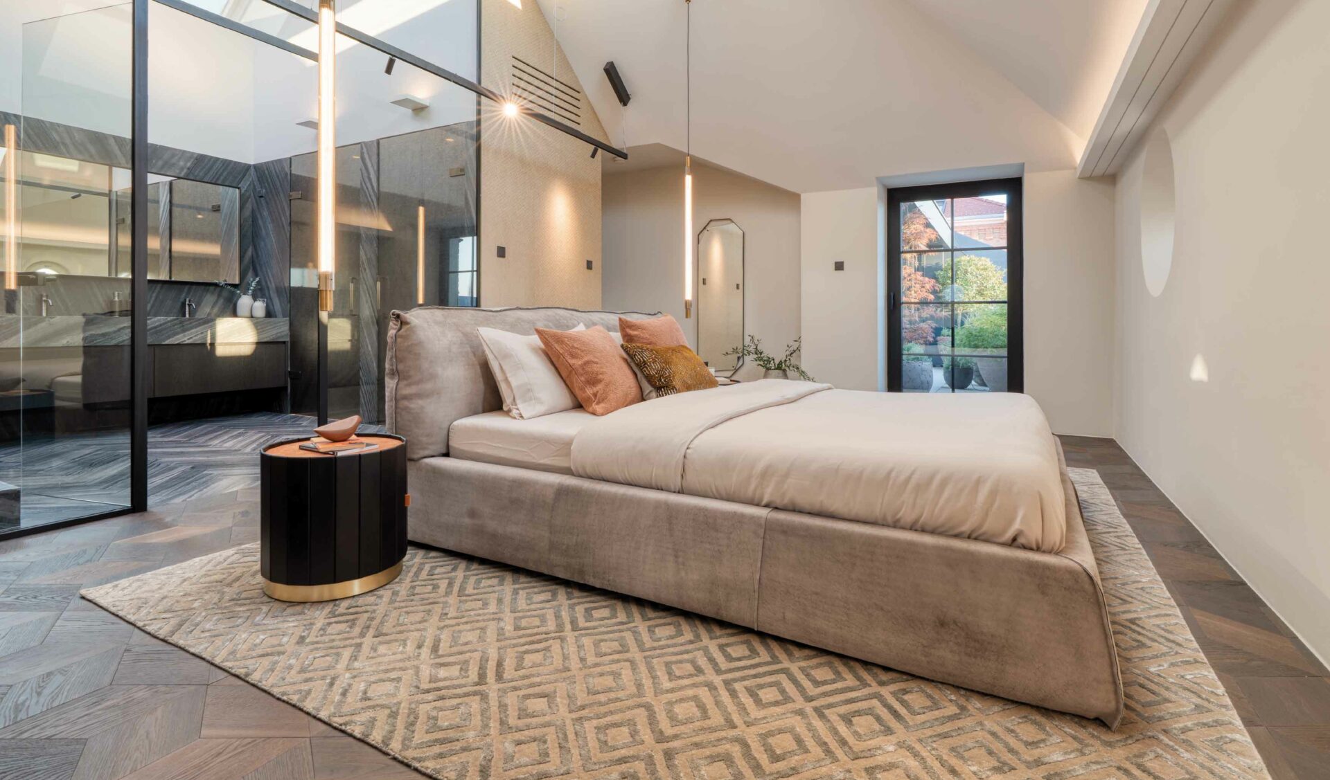 Modernes Schlafzimmer mit Ensuite-Bad, Polsterbett, Designerleuchten und Fischgrätparkett.