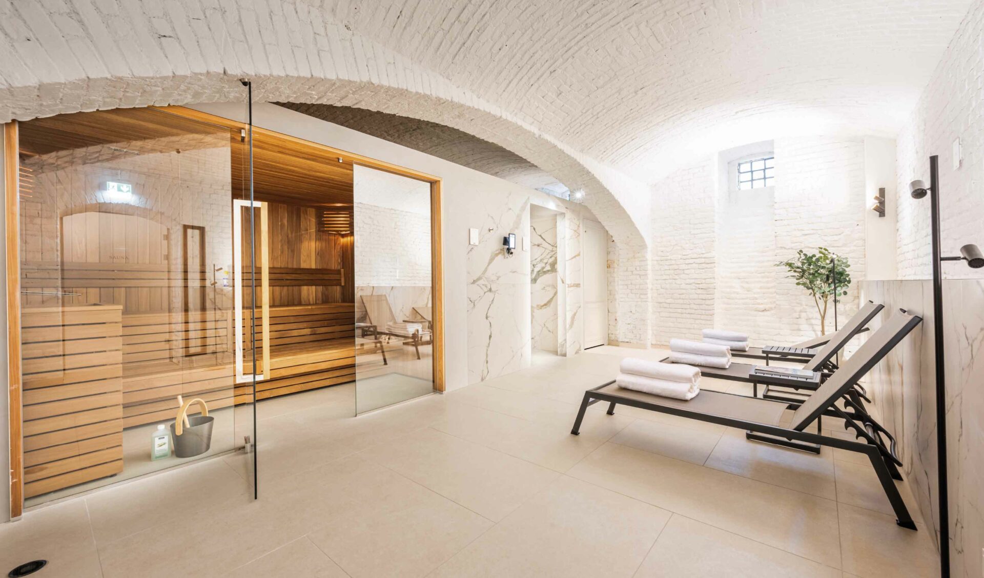 Privater Wellness-Bereich mit Sauna, Gewölbedecke und Ruheliegen.