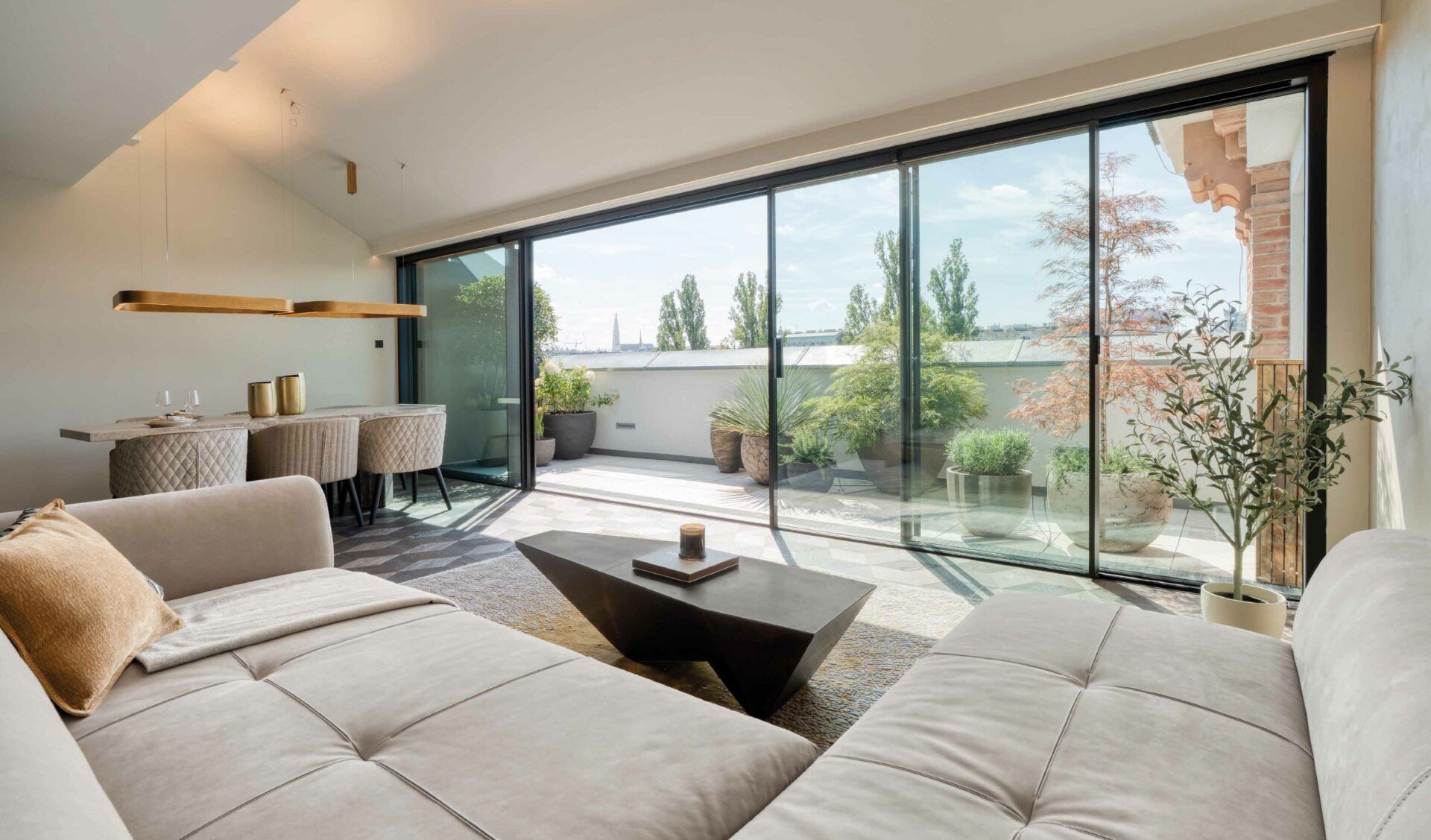 Helles Penthouse-Wohnzimmer mit bodentiefer Glasfront, großer Eckcouch und Terrassenzugang.