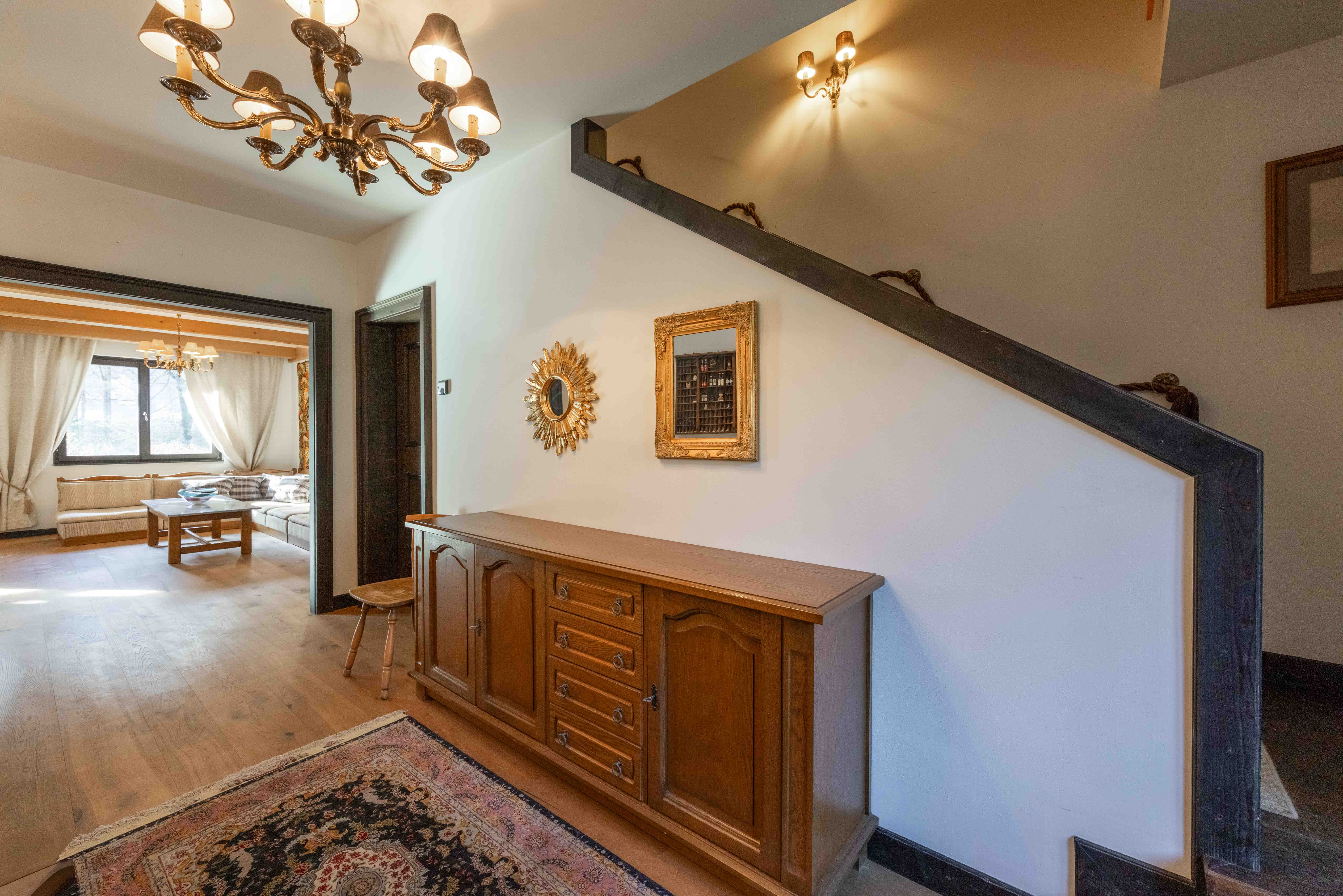 Flur im Landhausstil mit Kronleuchter, Holzsideboard und Blick ins Wohnzimmer.