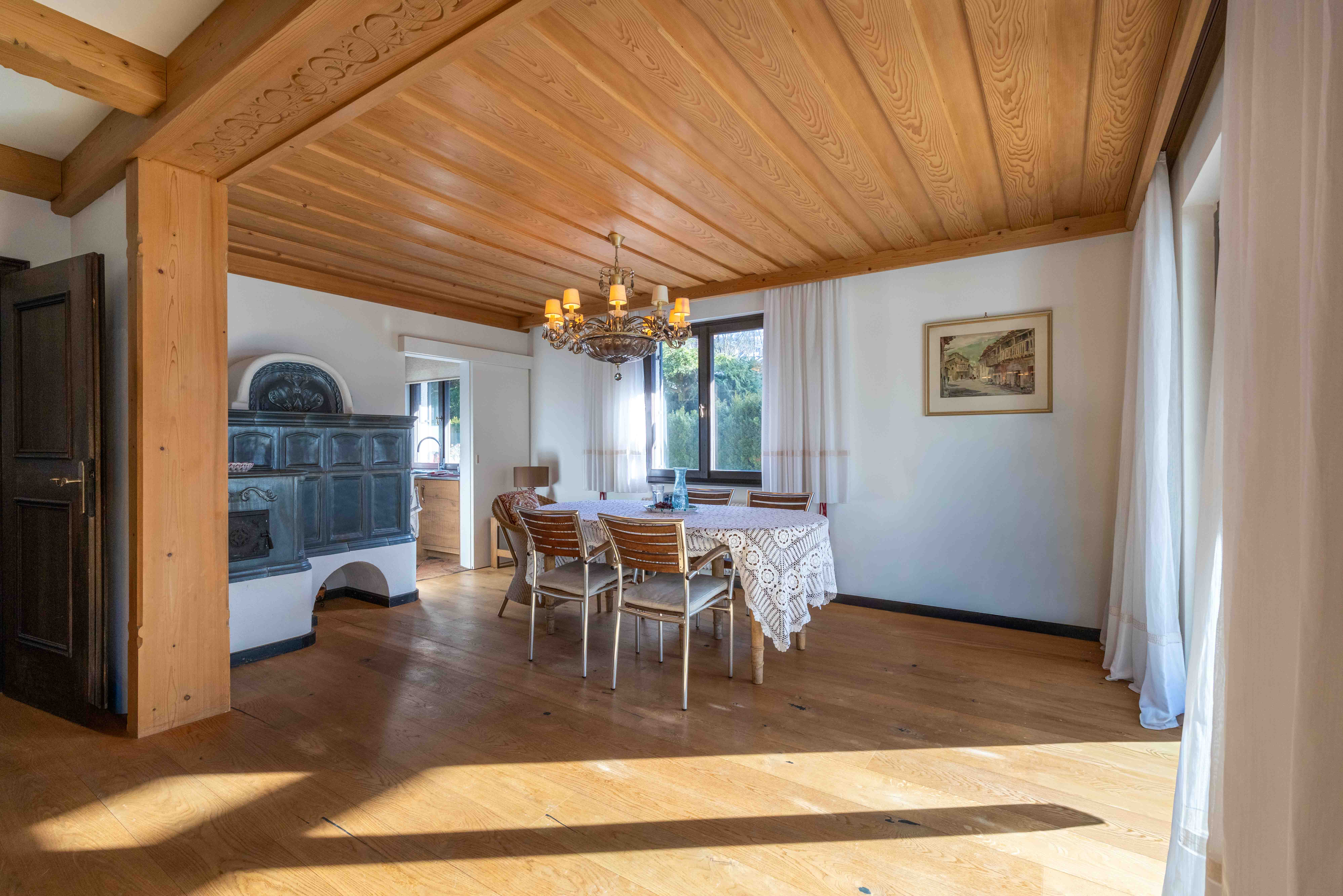 Helles Esszimmer mit Holzdecke, rustikalem Kronleuchter und Durchgang zur Landhausküche.