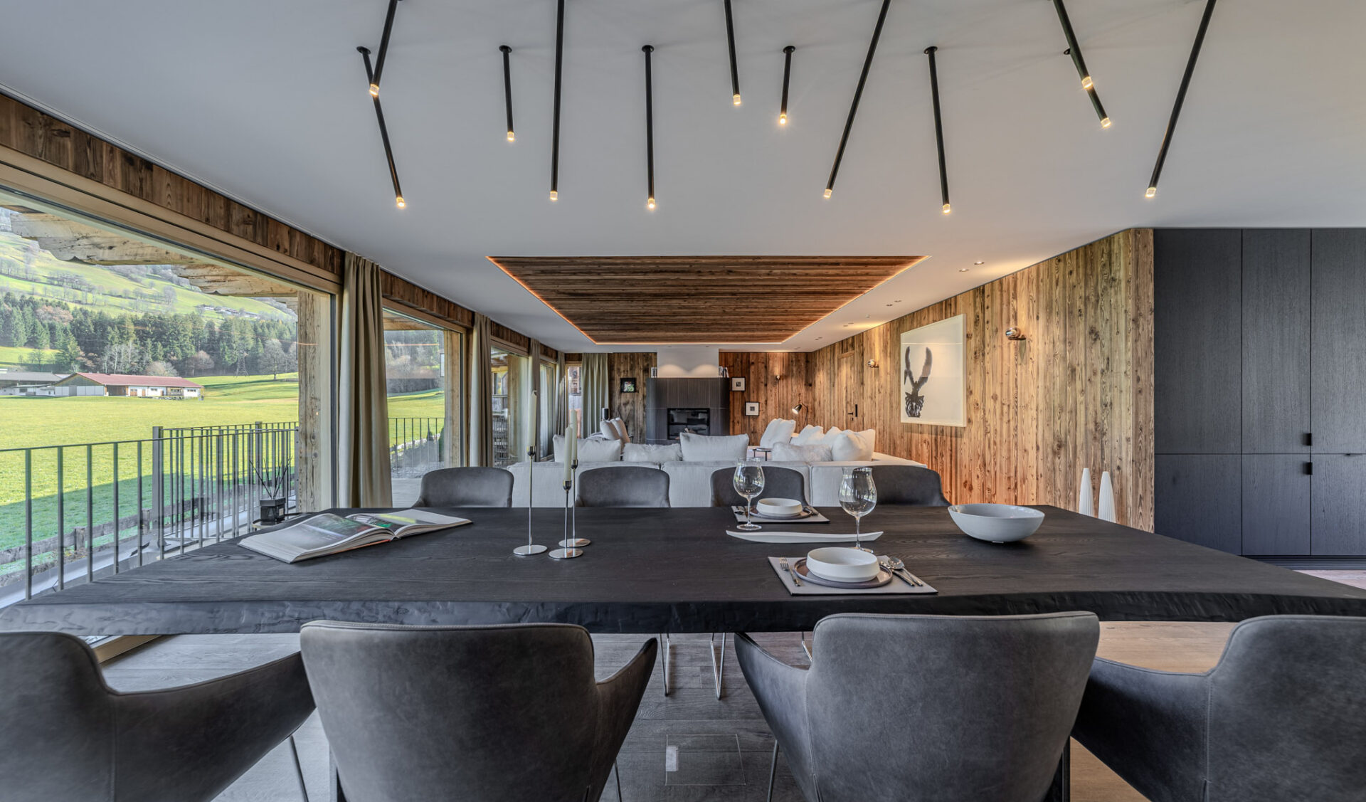 Modernes Chalet-Wohnzimmer mit Bergblick, Holzdecke und gemütlicher Einrichtung in Naturfarben.