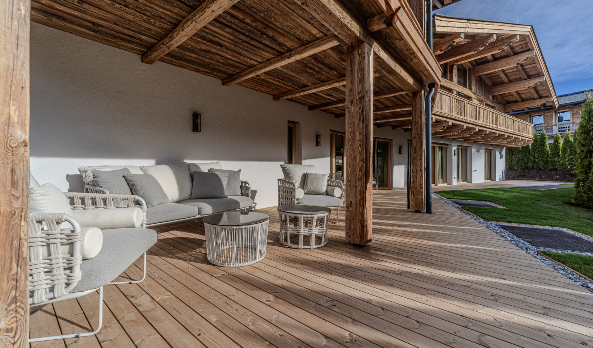 Außenterrasse einer Luxusgartenwohnung mit Lounge-Bereich und Gartenblick.