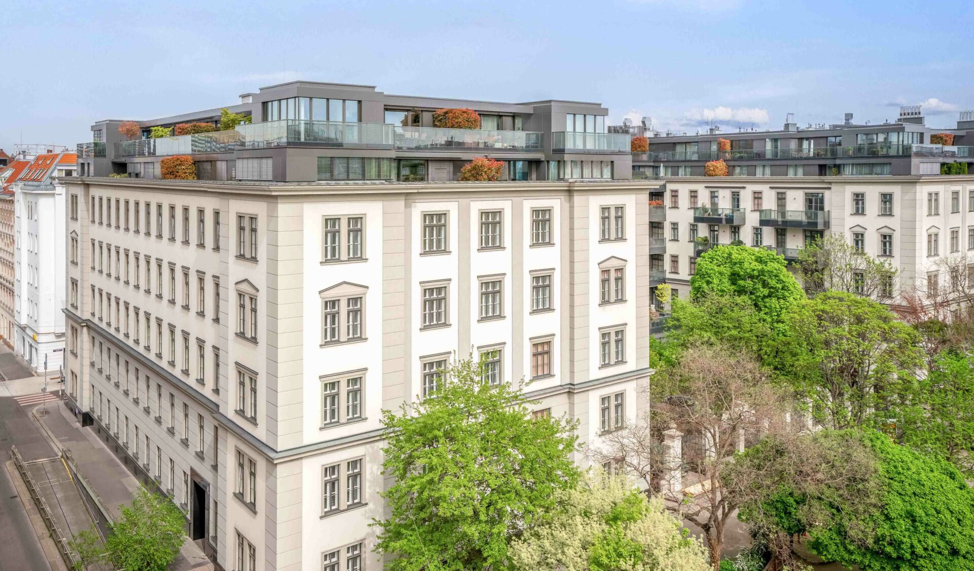 Sanierter Altbau mit modernen Penthouse-Aufbauten, begrüntem Innenhof und Glasfassaden.