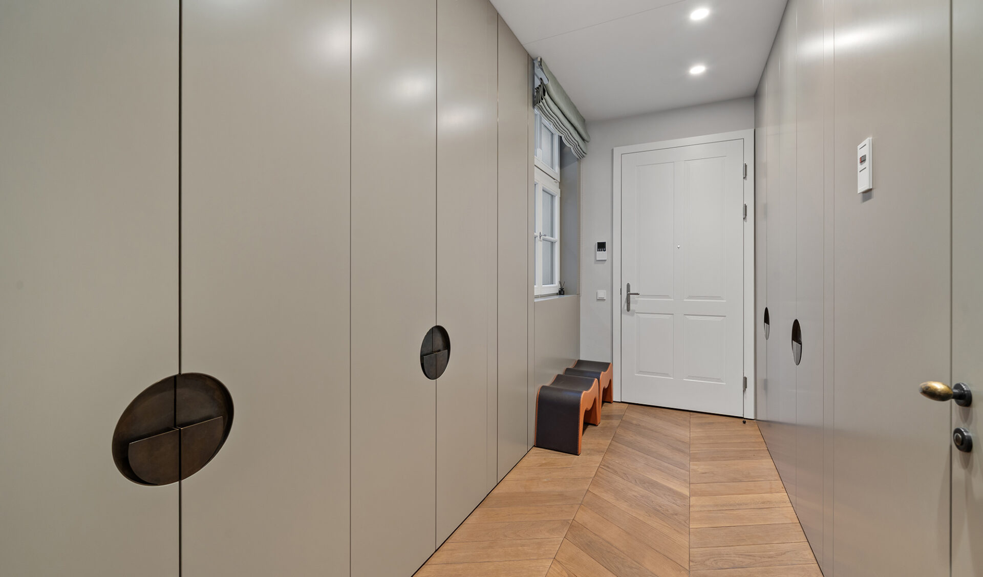 Neubau-Wohnung Eingangsbereich: moderne Flurgestaltung mit maßgefertigten Schränken, Parkettboden und integriertem Stauraum.