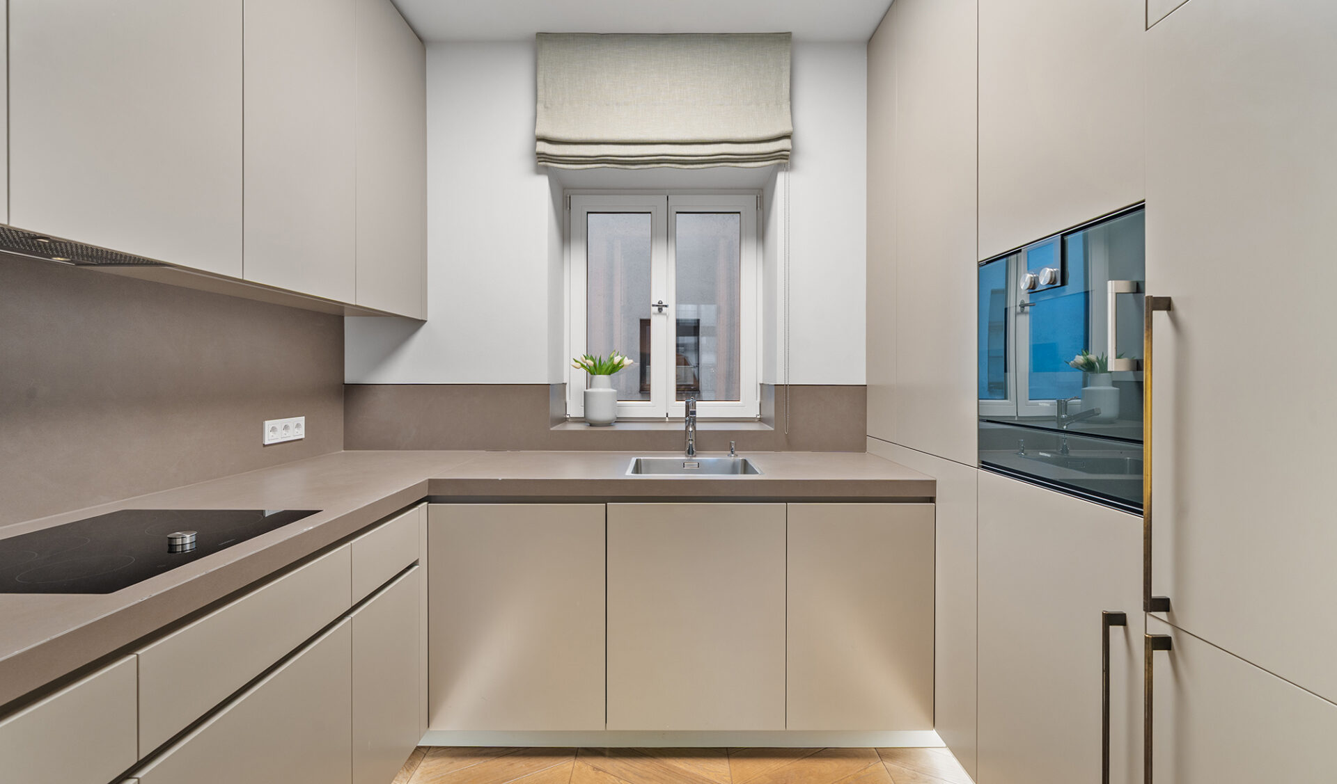 Komplett ausgestattete Küche einer Neubauwohnung mit hochwertigen Elektrogeräten, grifflose Schränken, Arbeitsplatte und Parkettboden.