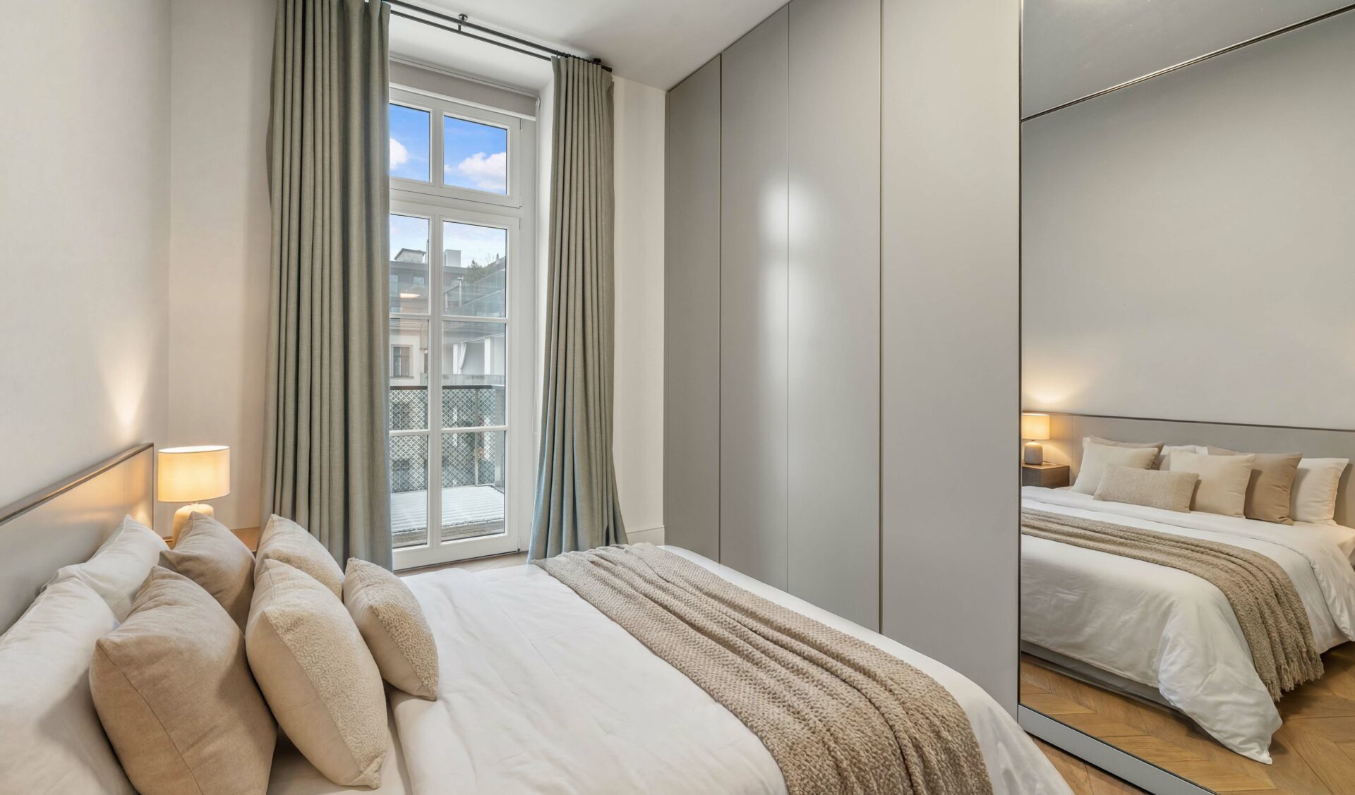 Neubau Schlafzimmer modern ausgestattet mit Einbauschränken, Spiegelfront, Balkon-Zugang und hochwertiger Ausstattung.