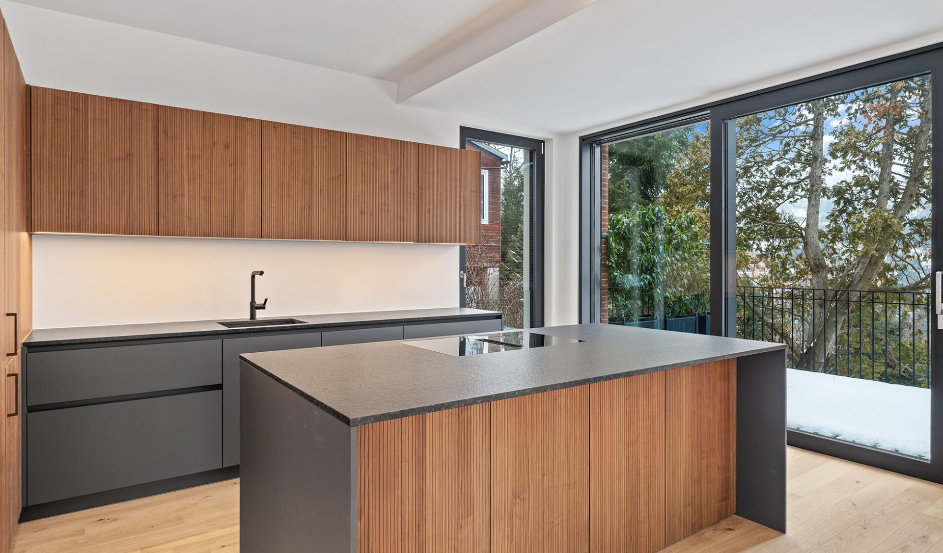 Moderne Designerküche mit großer Kochinsel, Holzfronten, indirekter Beleuchtung und Terrassenzugang.