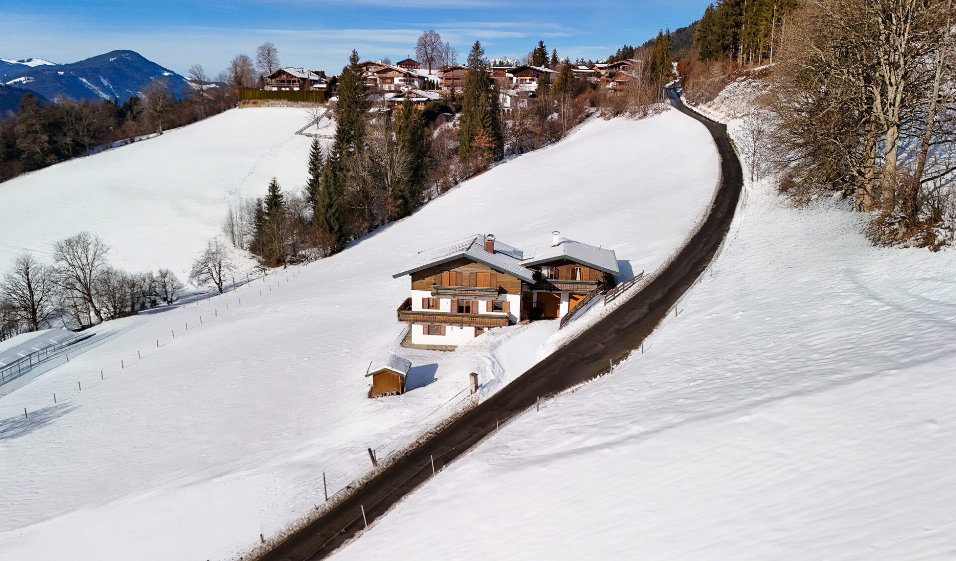 Traditionelles Alpenchalet im Schnee mit Bergpanorama auf der Bichlalm in Kitzbühel.