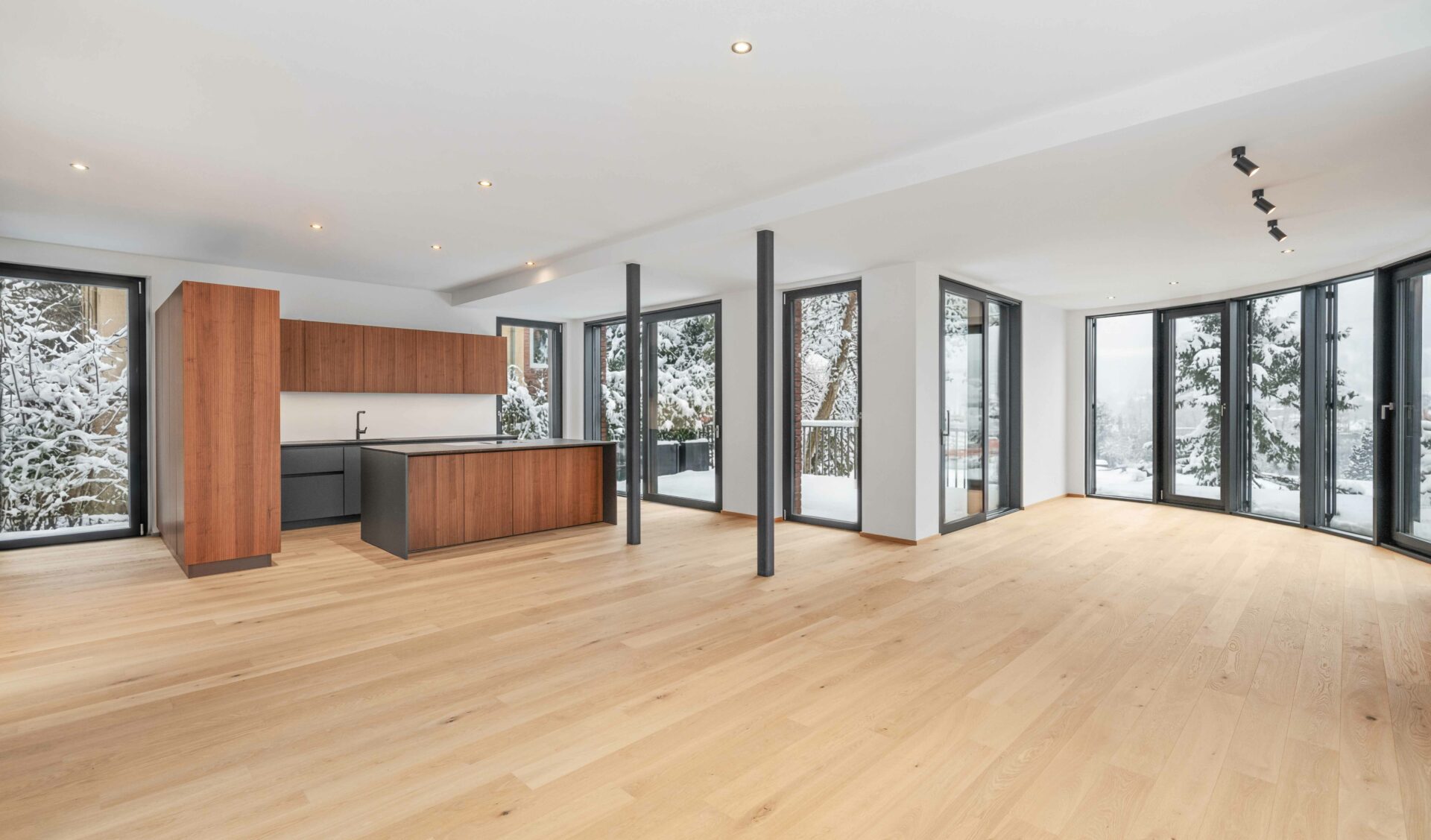 Offener Wohn-Essbereich mit Designer-Küche, Echtholzparkett und bodentiefen Fenstern mit Winterblick.