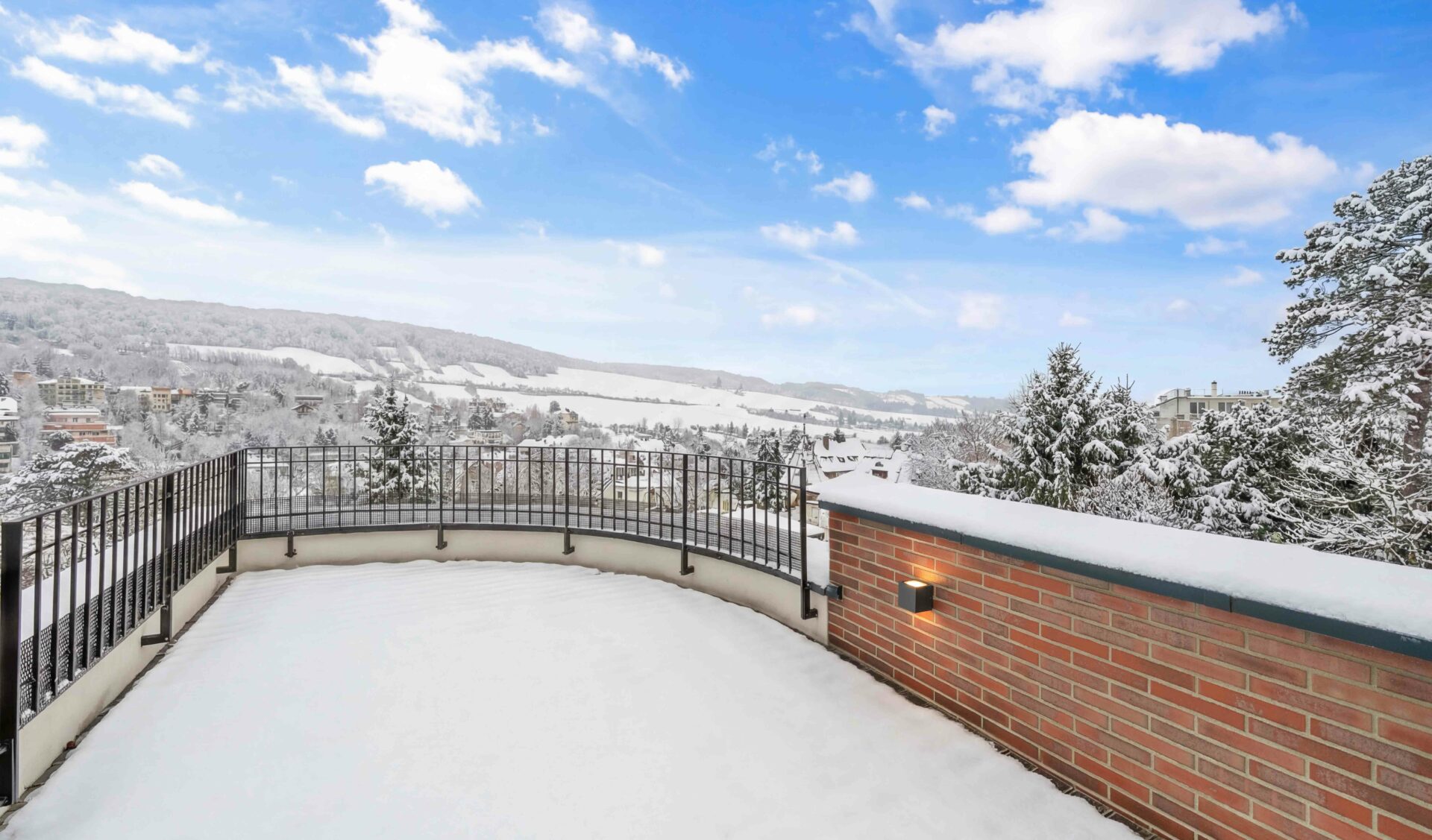 Großzügige Panoramaterrasse mit geschwungenem Geländer und 180-Grad-Blick auf Winterlandschaft und Weinberge.