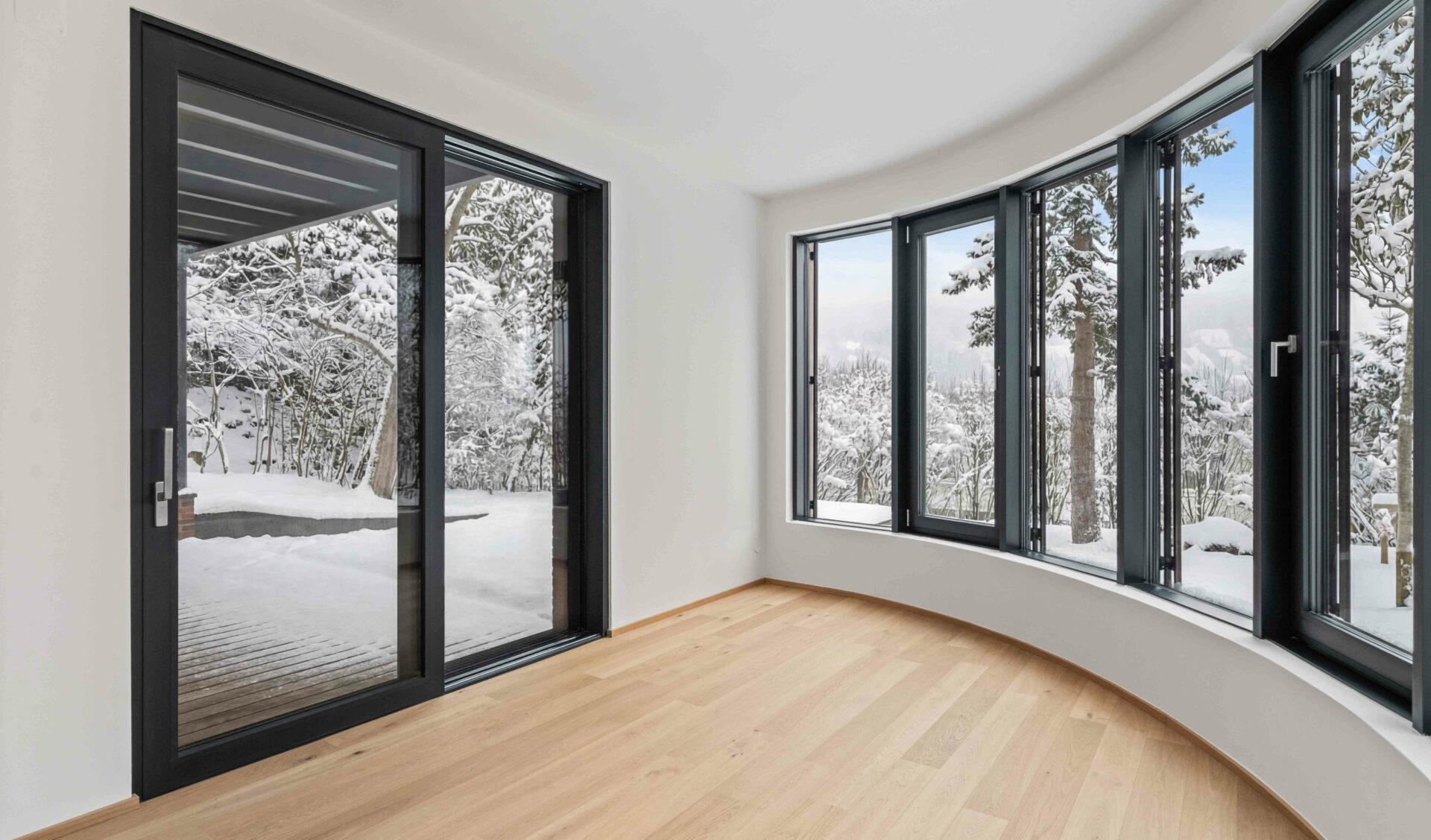 Heller Wohnraum im Rundturm mit 180-Grad-Verglasung, Terrassentür und Naturblick.