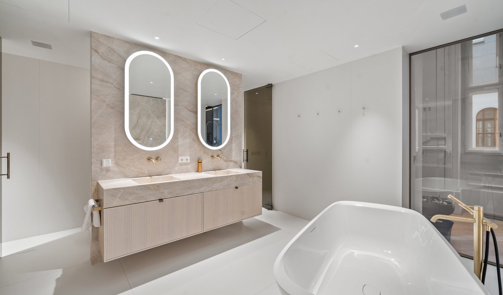 Premium-Badezimmer mit Travertin-Marmorwand, Doppelwaschtisch und freistehender Designbadewanne.