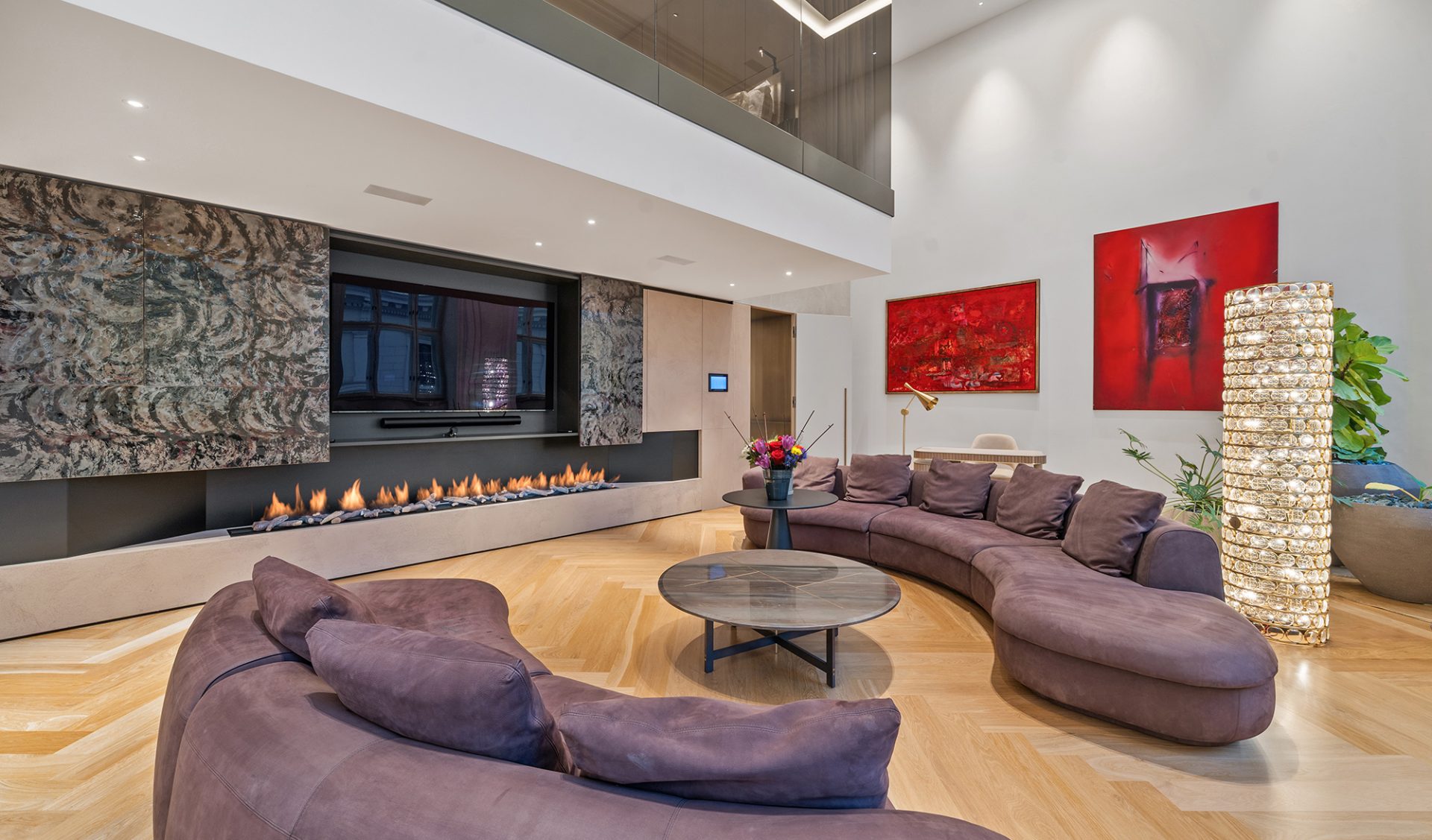 Exklusiver Wohnbereich mit linear Gaskamin, Natursteinverkleidung und geschwungenem Designer-Sofa.