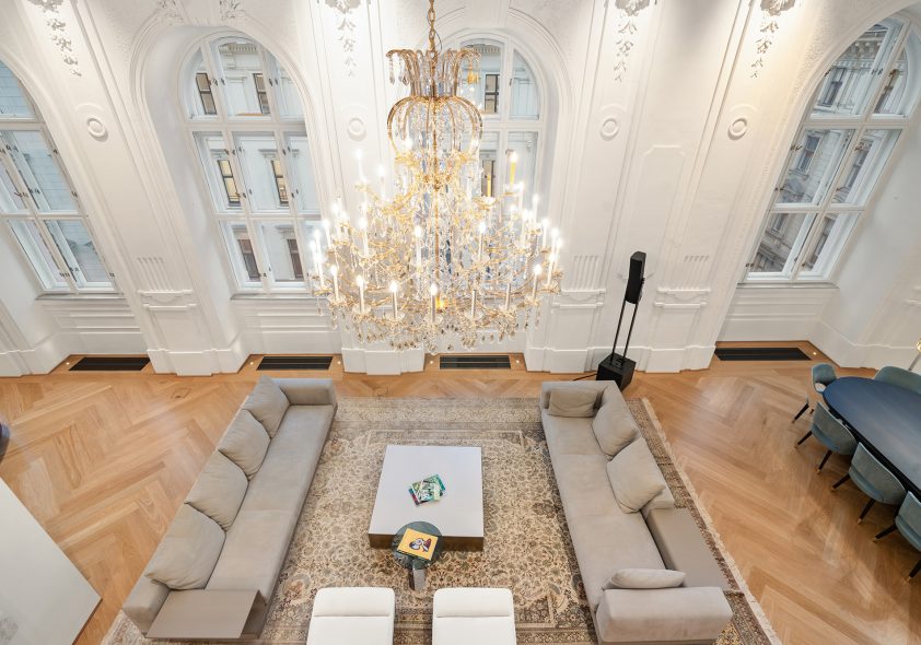 Großzügiger Maisonette-Wohnbereich mit historischem Stuck, Goldkronleuchter und modernem Interieur.