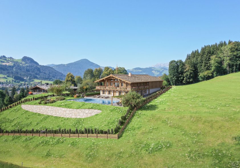 Spektakuläre Drohnenaufnahme eines Designer-Chalets in Südhanglage mit terrassiertem Garten, Pool und Alpenpanorama.