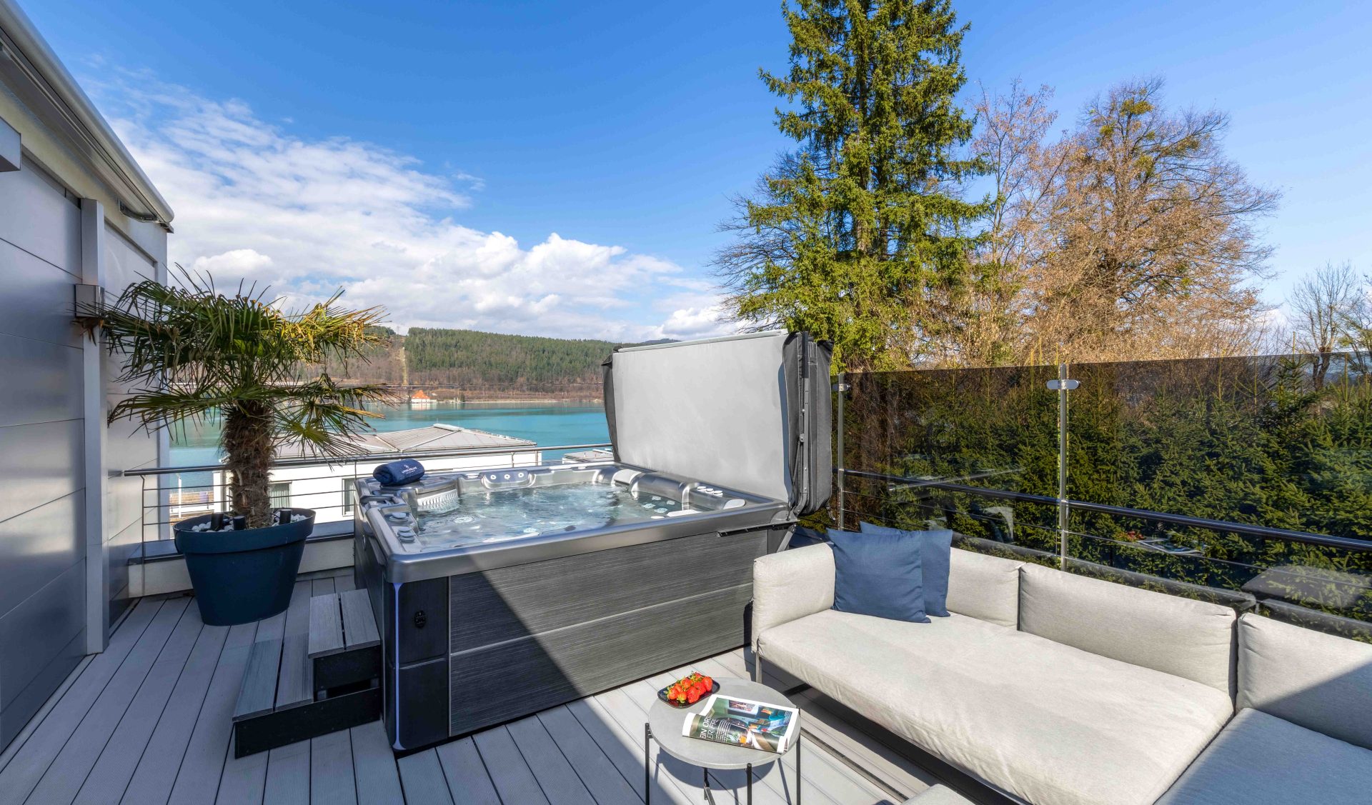 Moderner Outdoor-Whirlpool neben einer gemütlichen Lounge-Ecke und einem Beistelltisch mit Snacks und Zeitschriften.