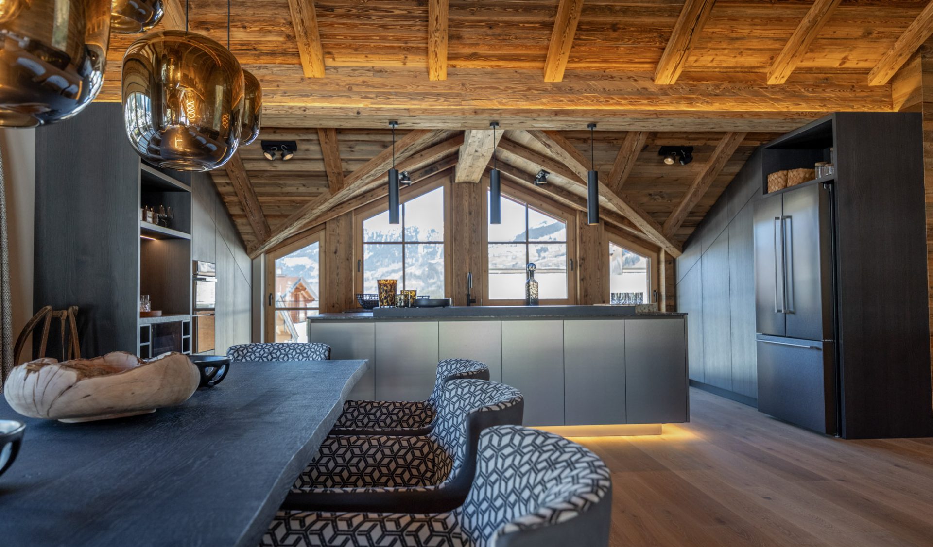Offener Wohn-Ess-Kochbereich mit Altholzbalken und Bergpanorama.