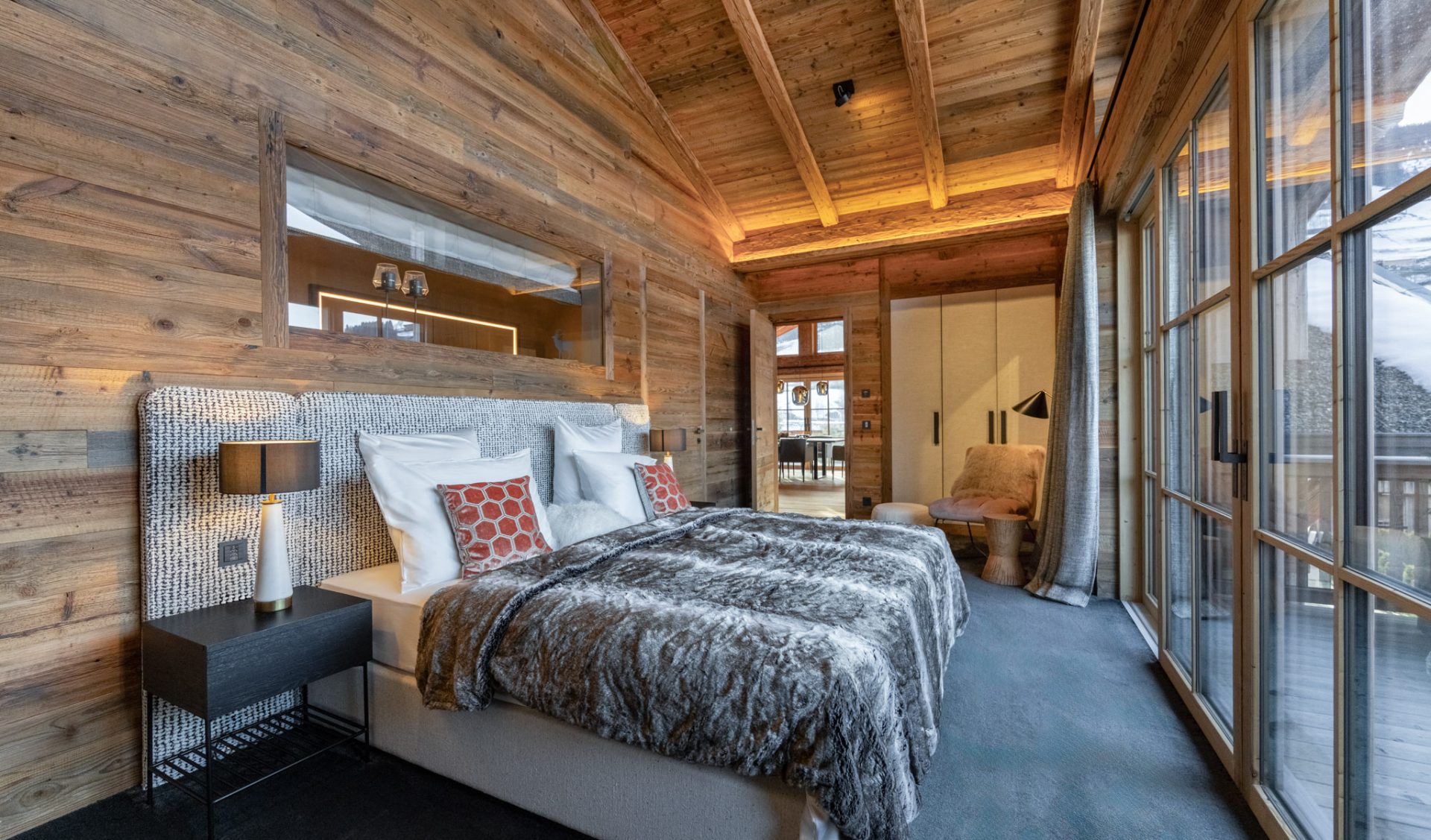 Luxuriöses Master-Schlafzimmer mit Altholzvertäfelung, Balkonzugang und alpinem Ambiente.