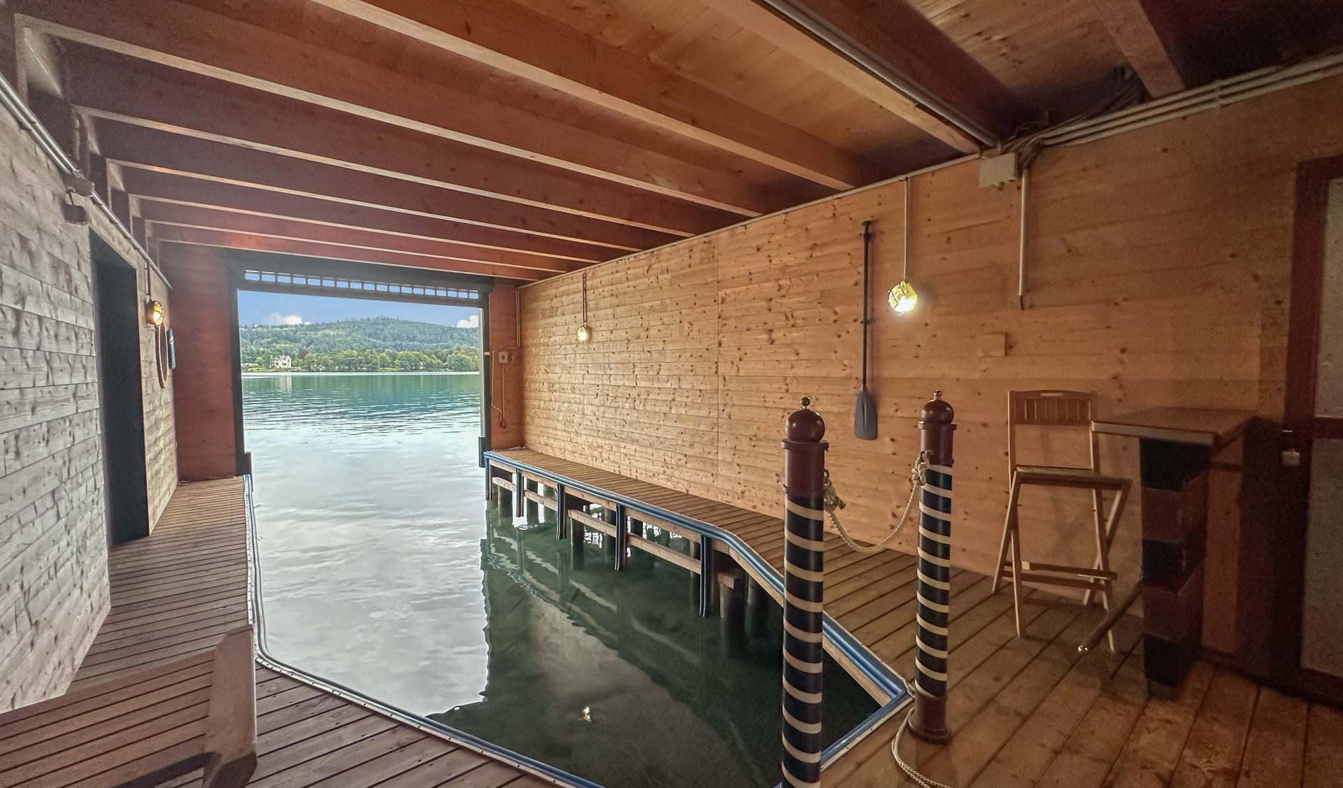 Innenansicht des Bootshauses aus Holz mit privatem Bootsliegeplatz, dekorativen Pollern und direktem Blick auf den Wörthersee.