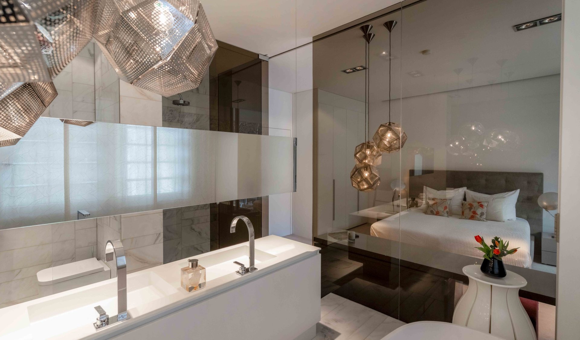 Hochwertiges Marmorbad mit Doppelwaschbecken, großem Spiegel und stilvoller Trennwand aus Glas zum Schlafbereich.