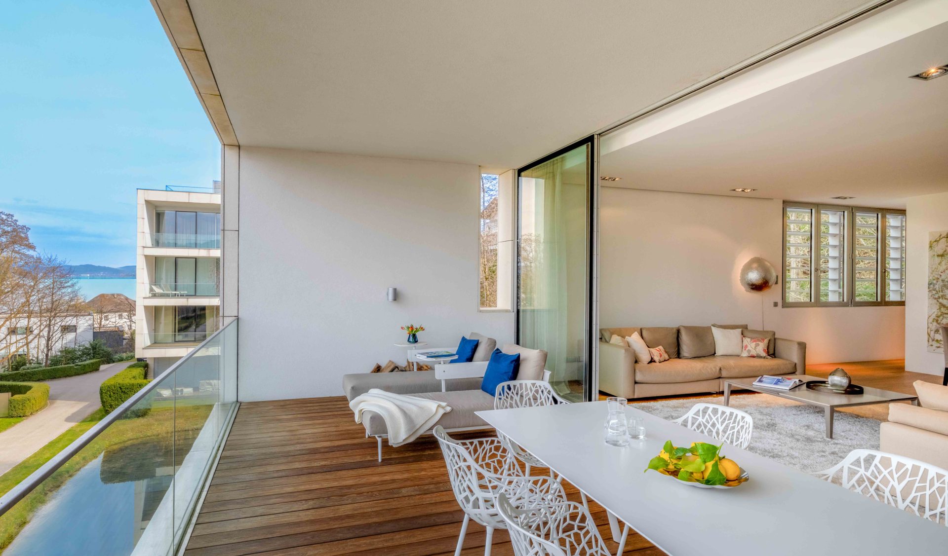 Überdachte Loggia des Design-Apartments im Schloss Velden mit Holzboden, modernen Outdoormöbeln und Blick auf den Wörthersee.