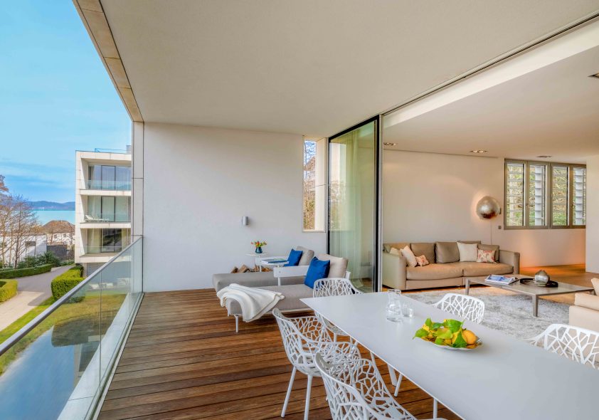 Überdachte Loggia des Design-Apartments im Schloss Velden mit Holzboden, modernen Outdoormöbeln und Blick auf den Wörthersee.