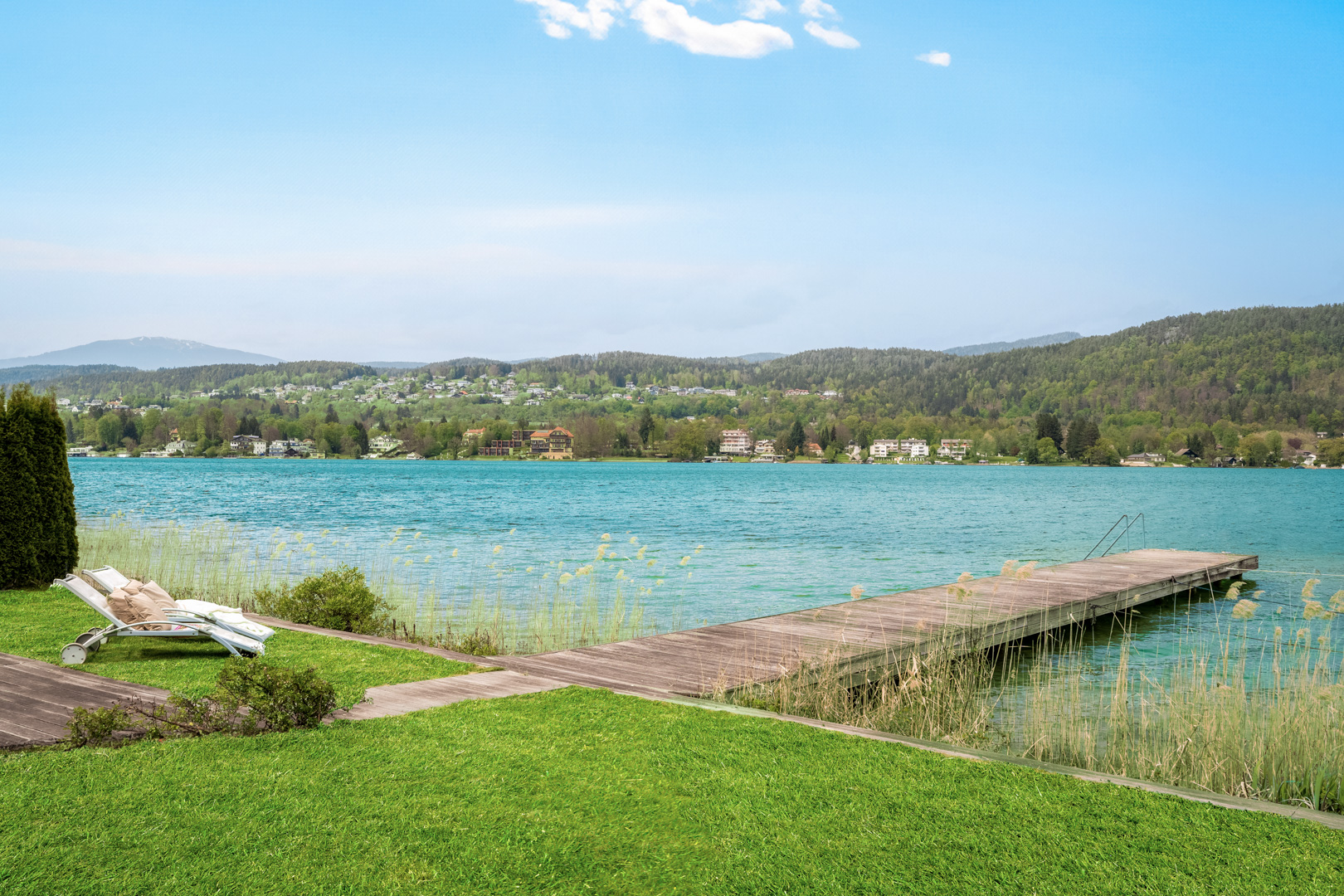 Privater Badesteg mit Liegewiese und Bootsanlageplatz vor türkisblauem Wörthersee.