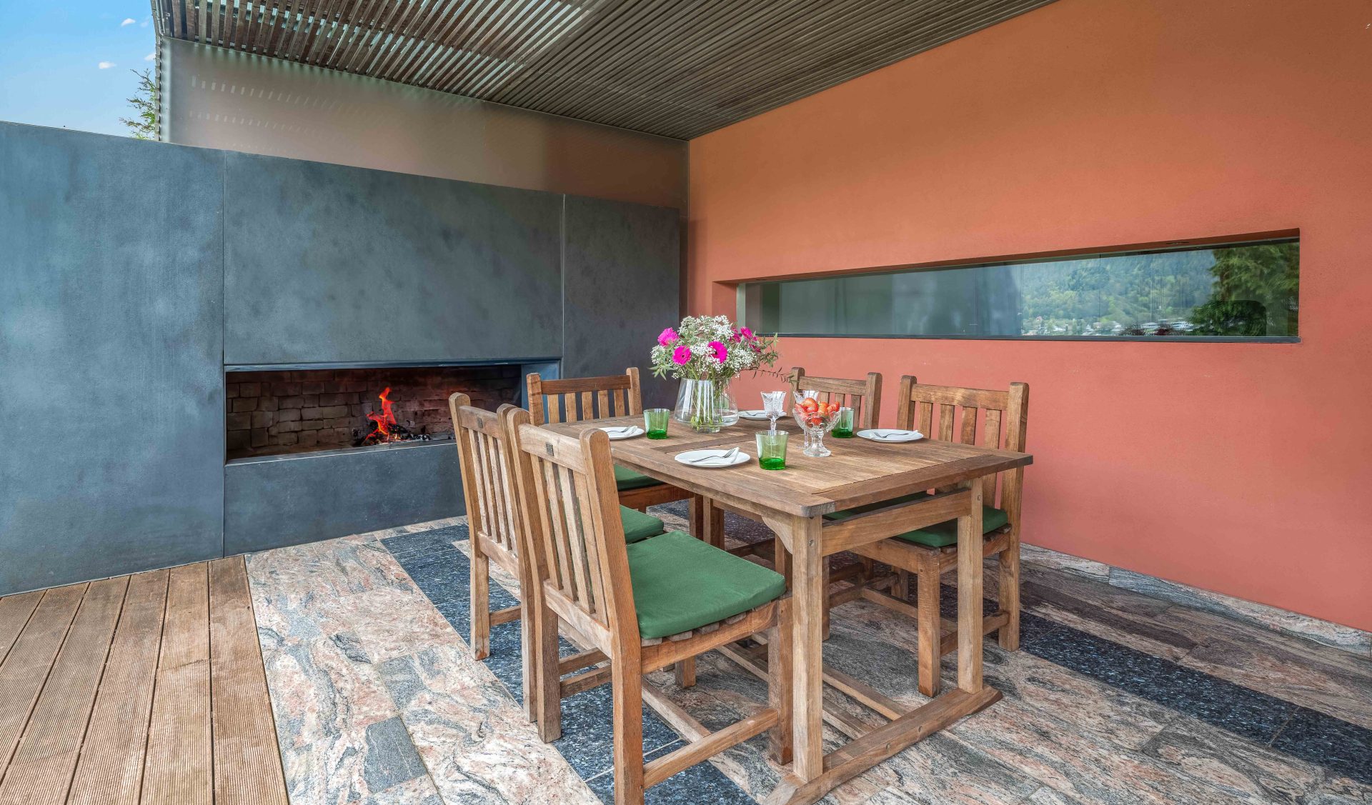Überdachte Außenterrasse mit modernem Kamin und gedecktem Terrassentisch.