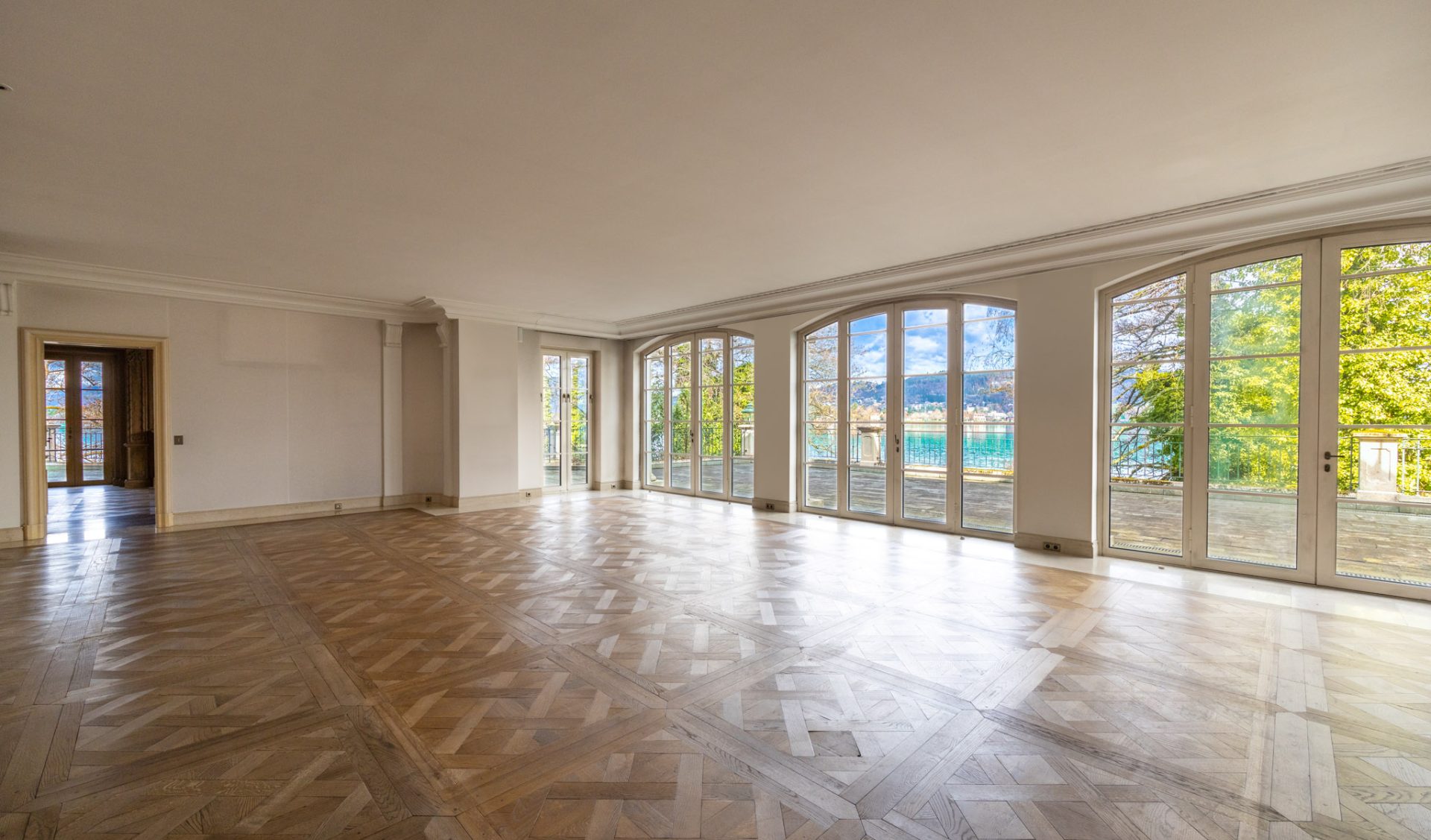 Repräsentativer Salon mit Sternparkett und Panoramafenstern mit Blick auf den Wörthersee.