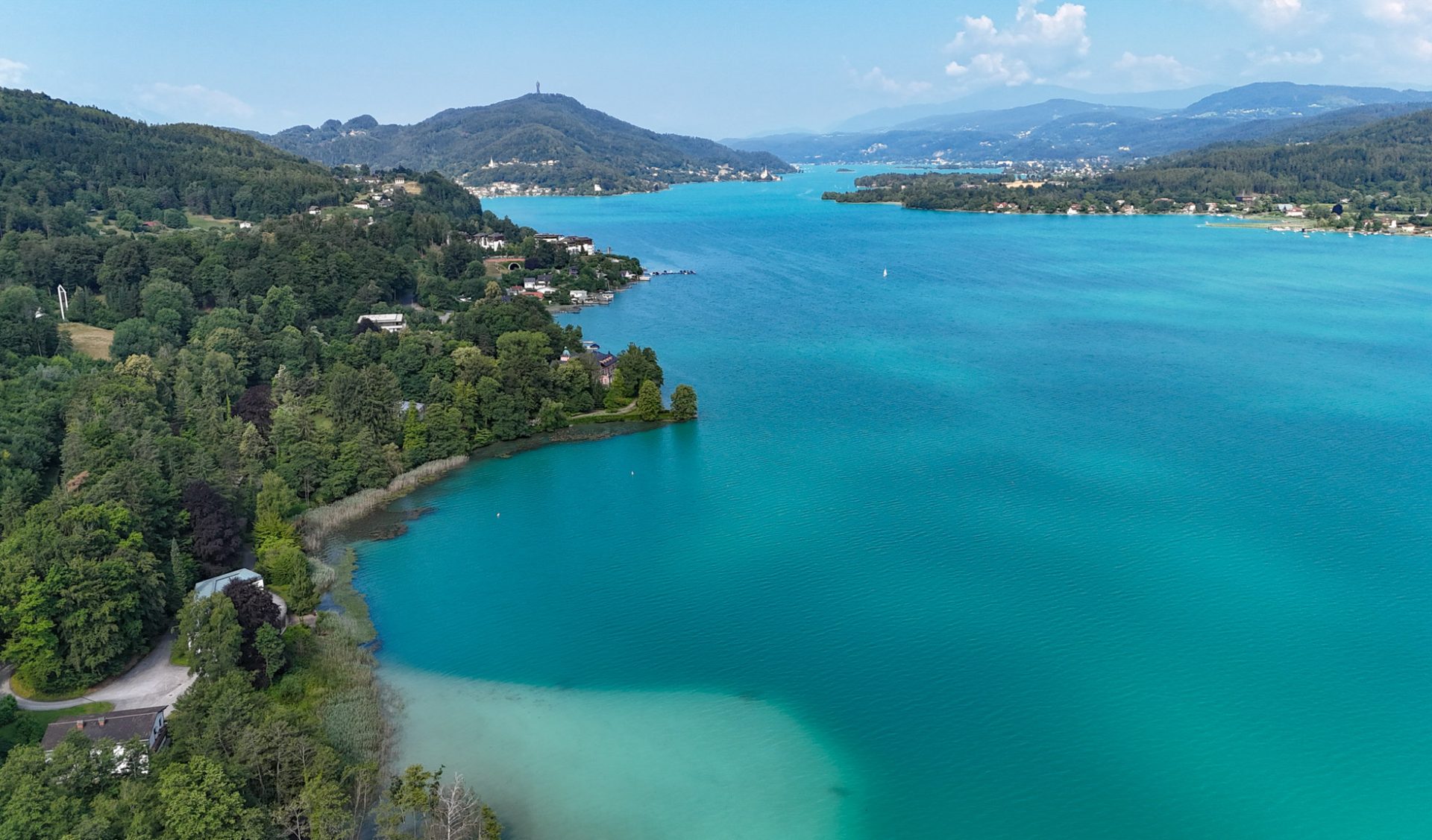 Weitläufiges Wörthersee-Panorama mit türkisblauem Wasser und dem Sekirner Südufer.